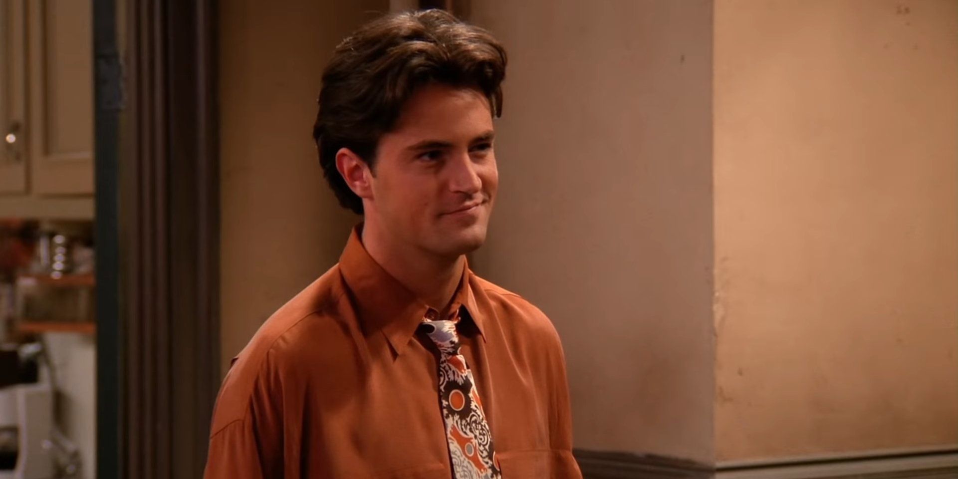 Chandler Bing smiles in a hallway in Friends