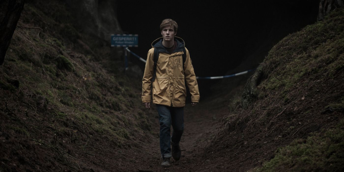 A young man walking in the dark outdoors in Dark