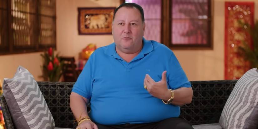 David 90 Day Fiance in blue shirt sitting on couch for confessional interview