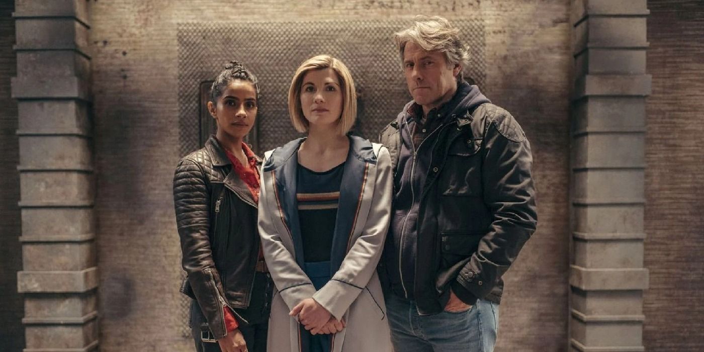 The Doctor, Yaz, and Dan looking forwards against a stone wall