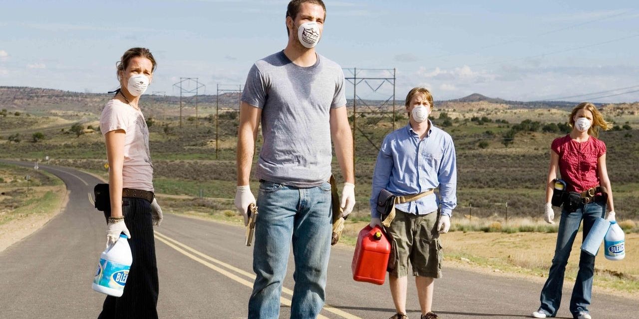 Four people walk on a deserted road wearing masks in Carriers 