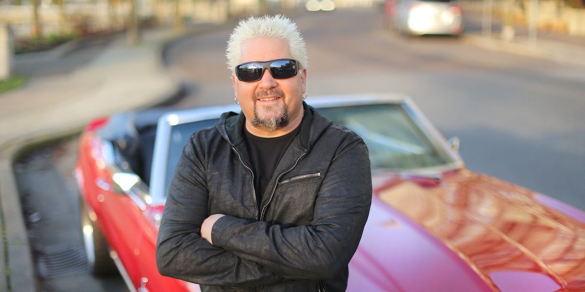 Guy Fieri leans against a car in Diners, Drive-Ins, and Dives 