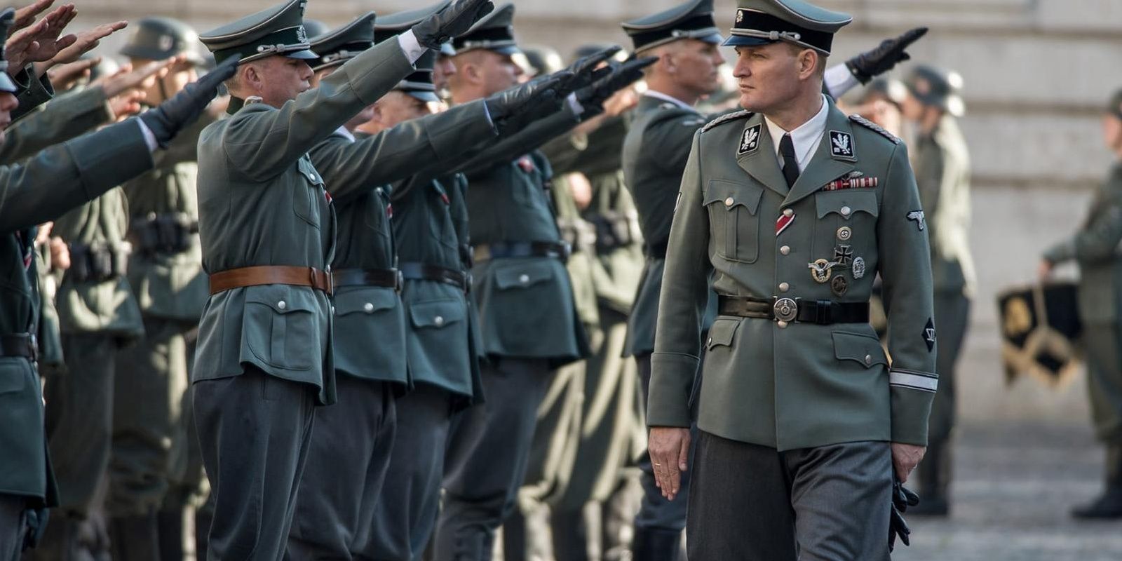 Jason Clarke walks as soldiers offer the Nazi salute in a still from The Man With The Iron Heart