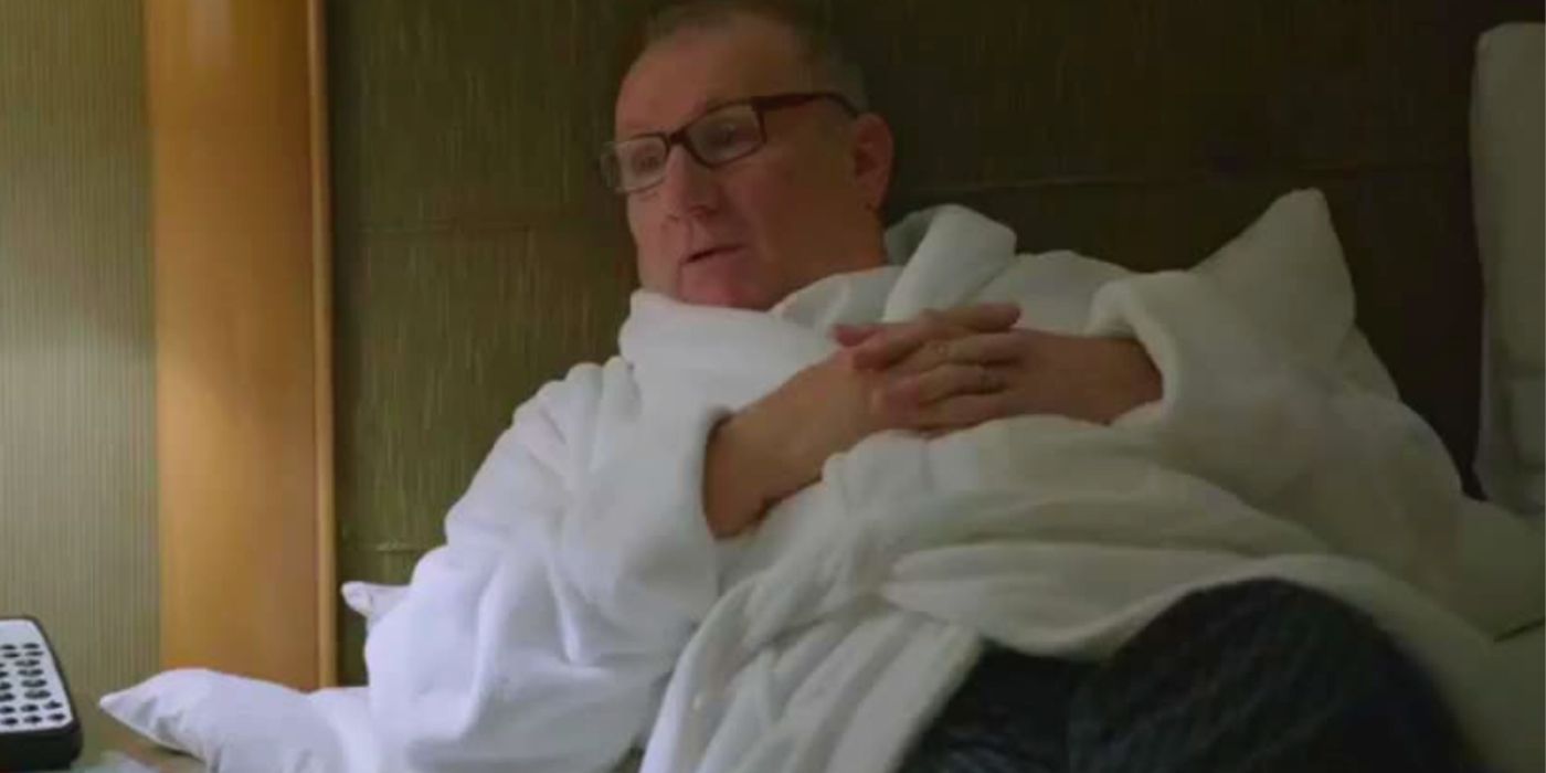 Jay lying in bed at a hotel on Modern Family