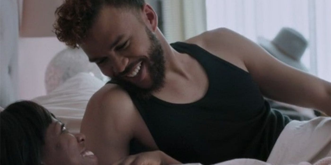 Jidenna smiling and looking at Yvonne Orji on bed in Insecure