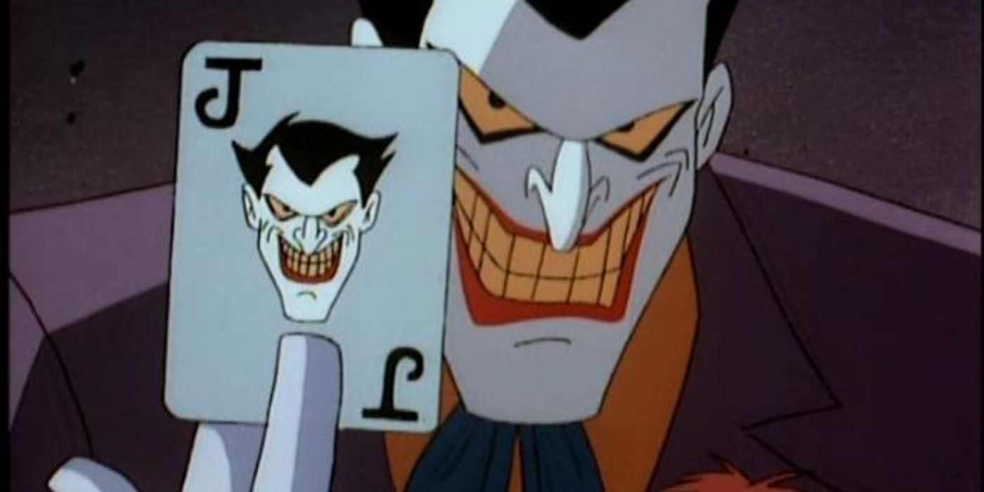 Joker chuckling maniacally while holding up his trademark playing card