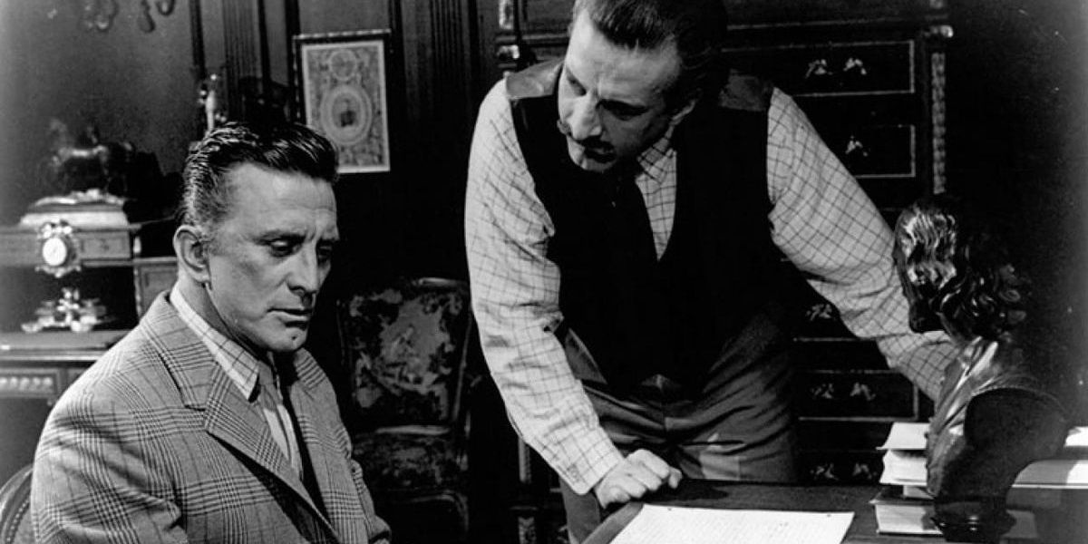Kirk Douglas sitting at a desk in The List of Adrian Messenger