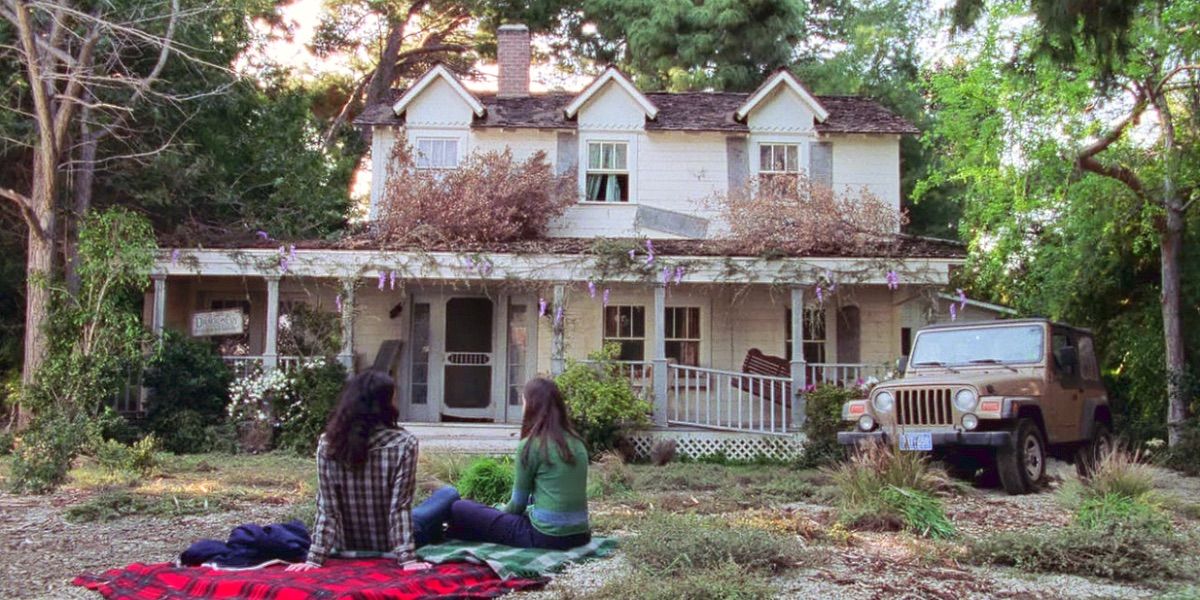 Two women sit in front of the dilapidated Dragonfly inn in Gilmore Girls