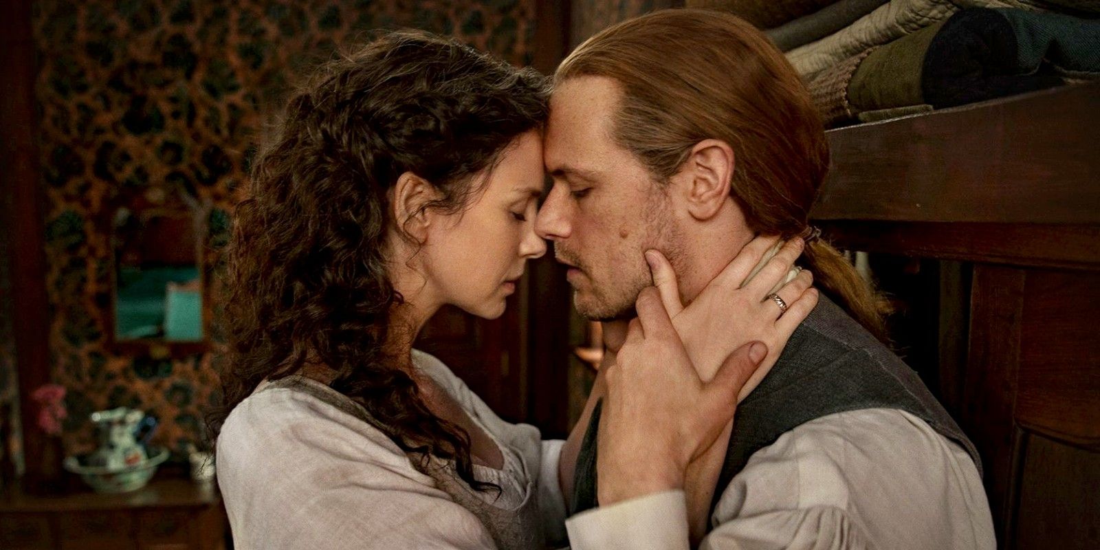Jaime and Claire stand faces touching in Outlander