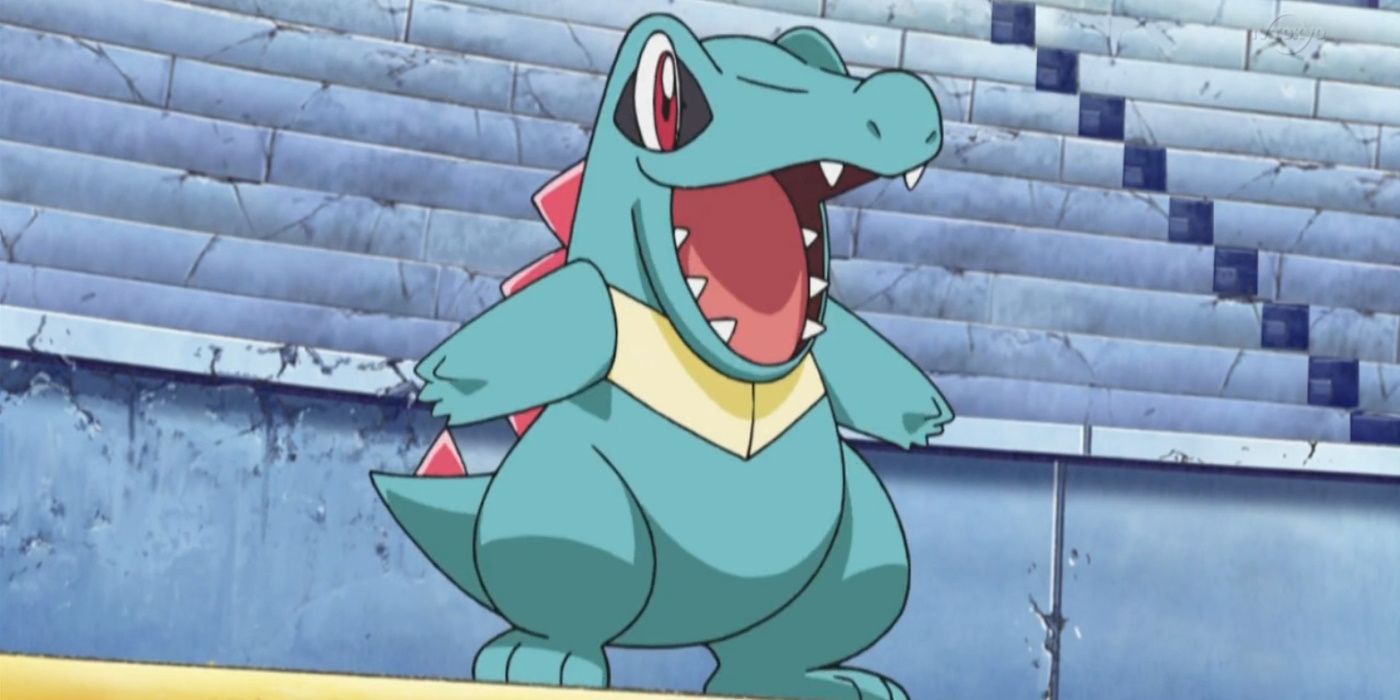 Totodile smiles widely in the middle of a deserted arena in Pokémon.