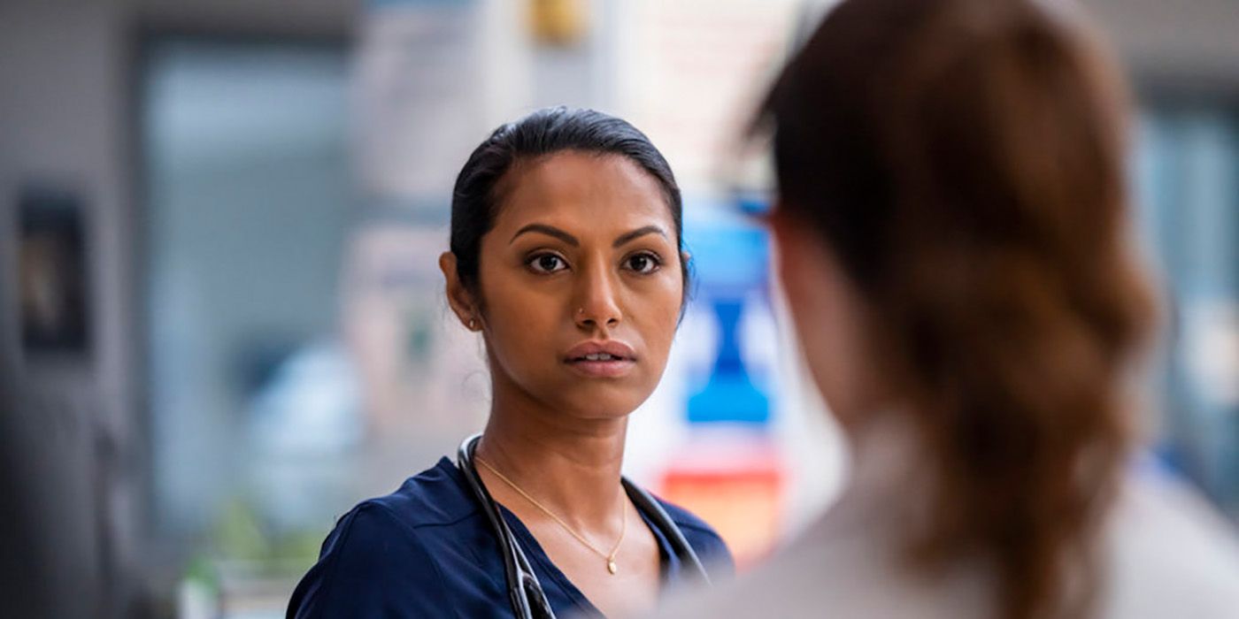 Leyla from New Amsterdam looking upset while talking to Lauren, wearing her blue scrubs.