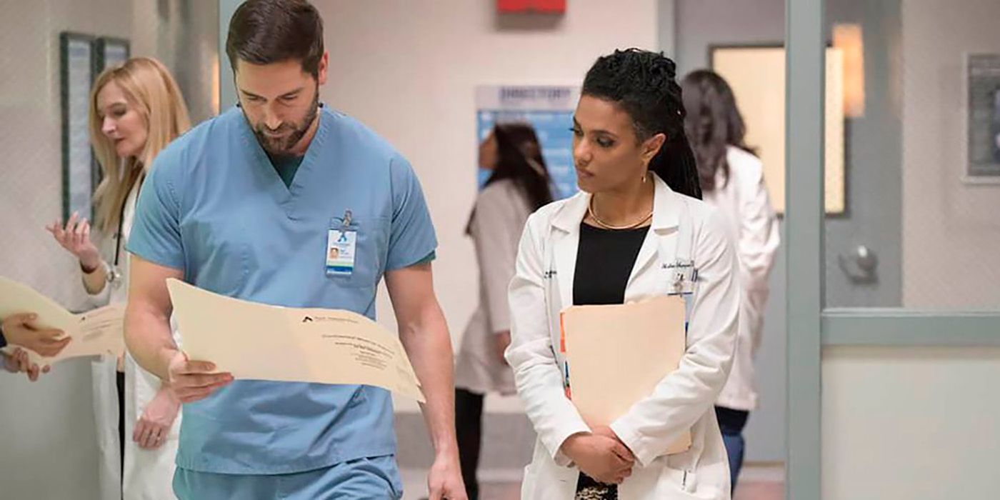 Max and Helen from New Amsterdam walking down the hospital hallway together, looking at patient files.