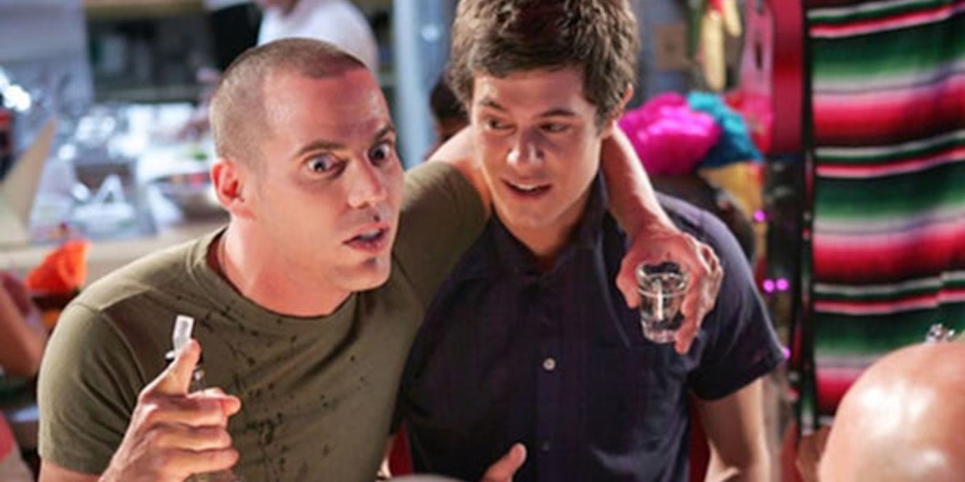 Steve-O hangs on Adam Brody while holding a shot glass and bottle in The O.C.