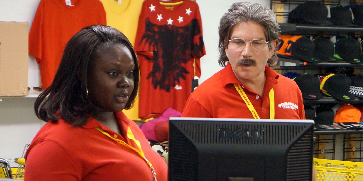 The CEO of Forman Mills in disguise looking at a cash terminal with an employee in a scene from Undercover Boss.