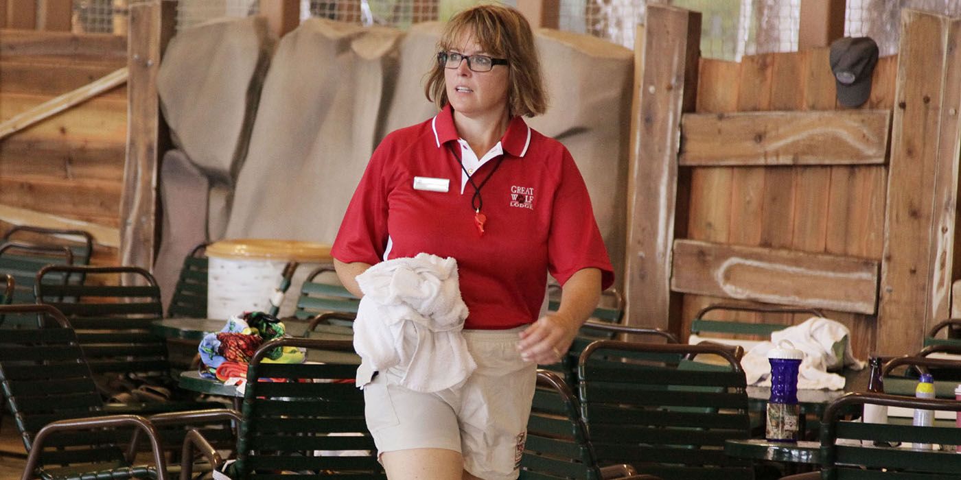 The CEO of Great Wolf Resorts walking through a resort holding a towel in an episode of Undercover Boss.