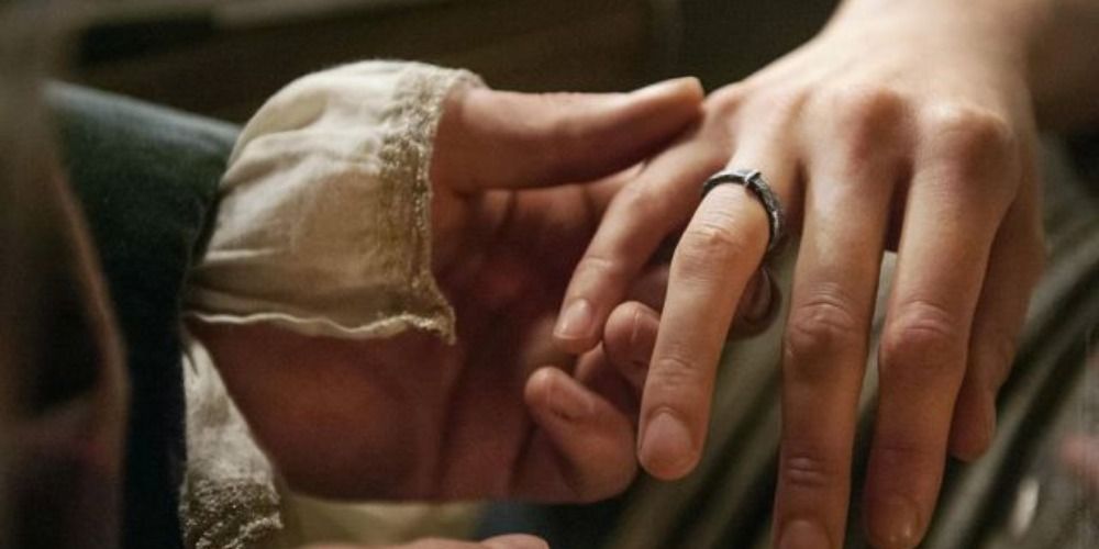 An image of Jamie putting a ring on Claire's finger in Outlander