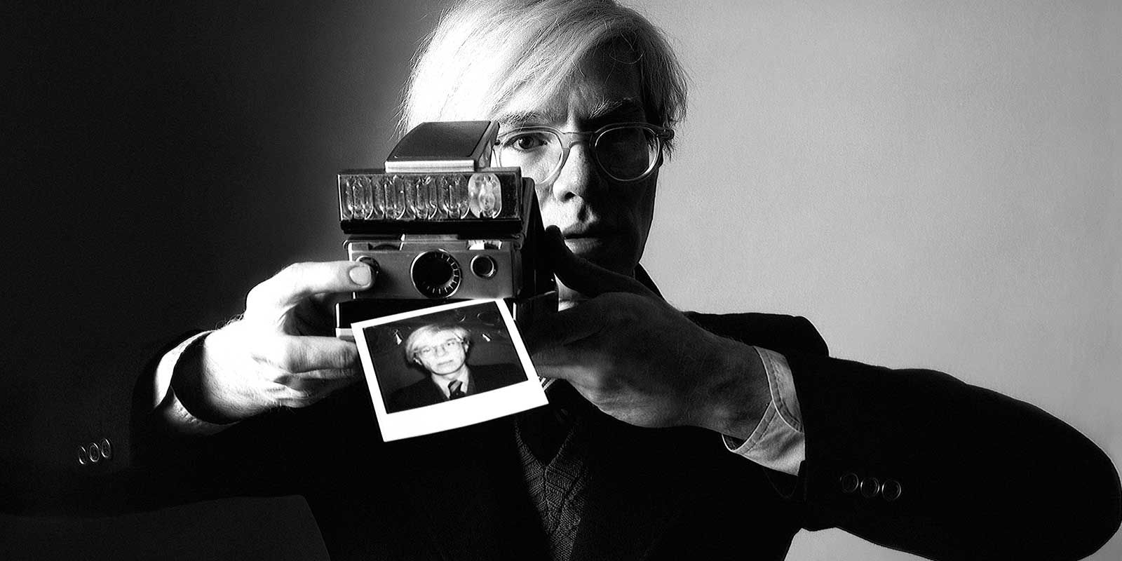 Andy Warhol holding a polaroid camera