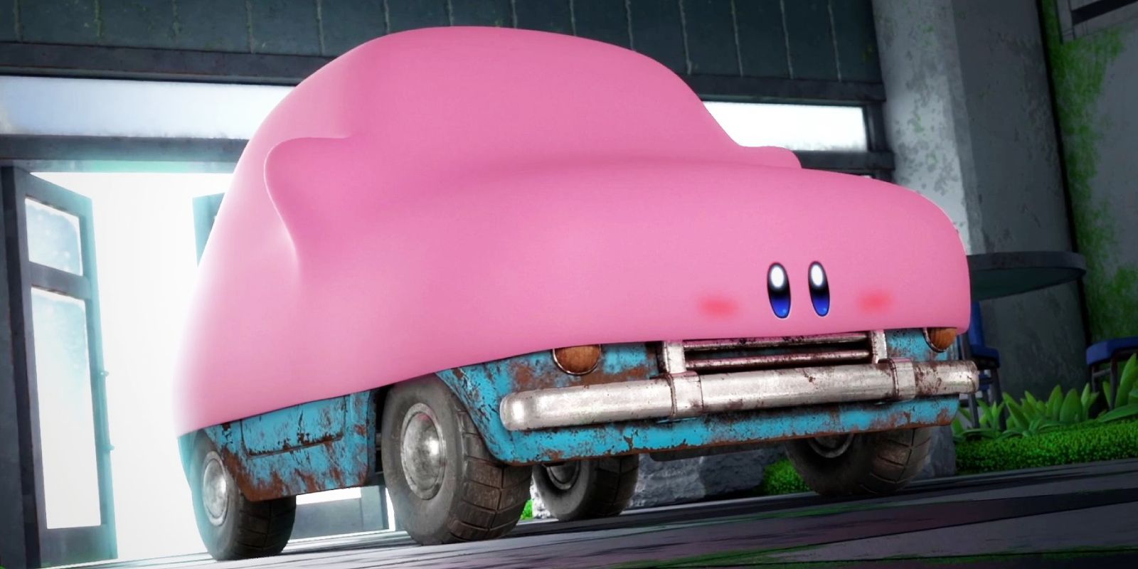 Kirby usando o novo modo Mouthful de Forgotten Land para se esticar sobre um carro velho.  Os olhos de Kirby estão na frente da grade e as rodas do carro saem de sua boca.