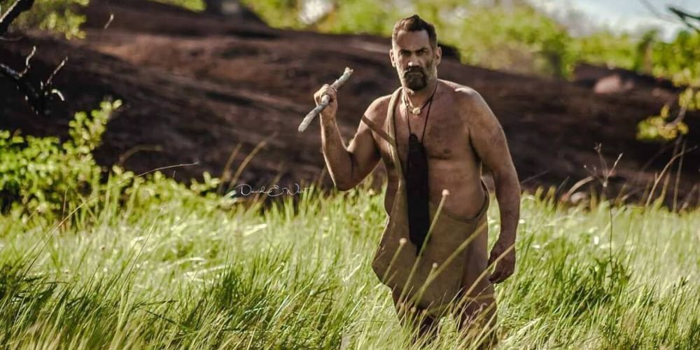 EJ carries a spear through the grass in Naked and Afraid