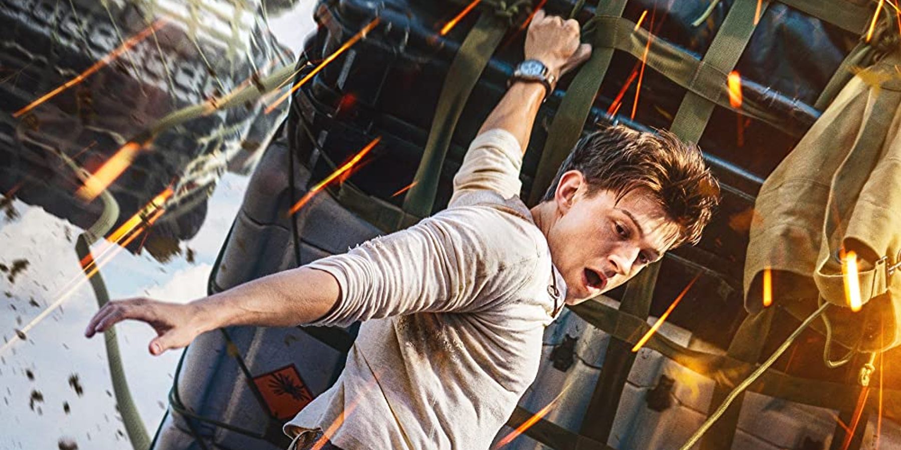 Nathan Drake hanging from cargo dangling from a plane in poster artwork for Uncharted