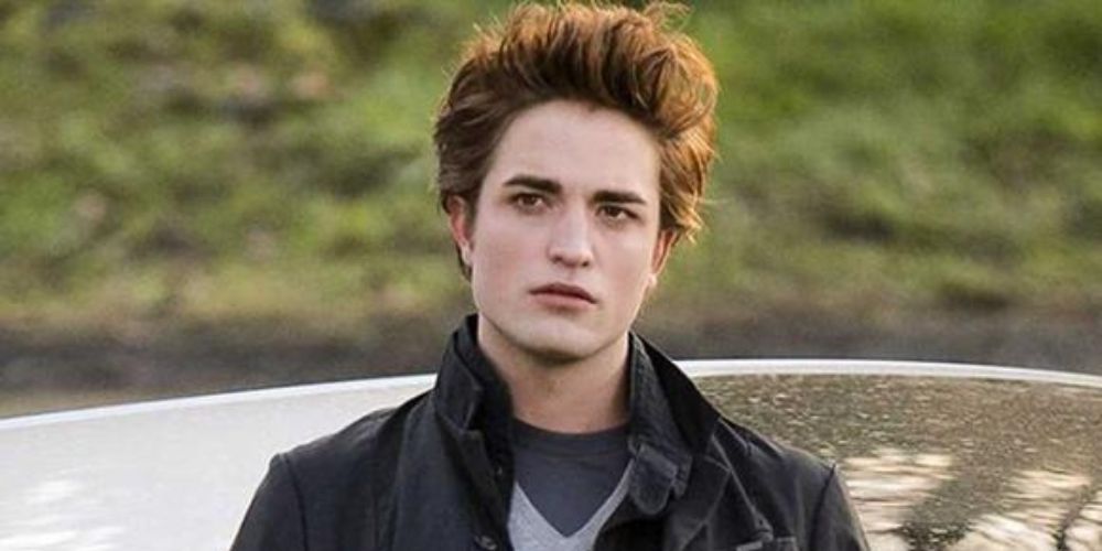 Robert Pattinson as Edward Cullen standing by a car