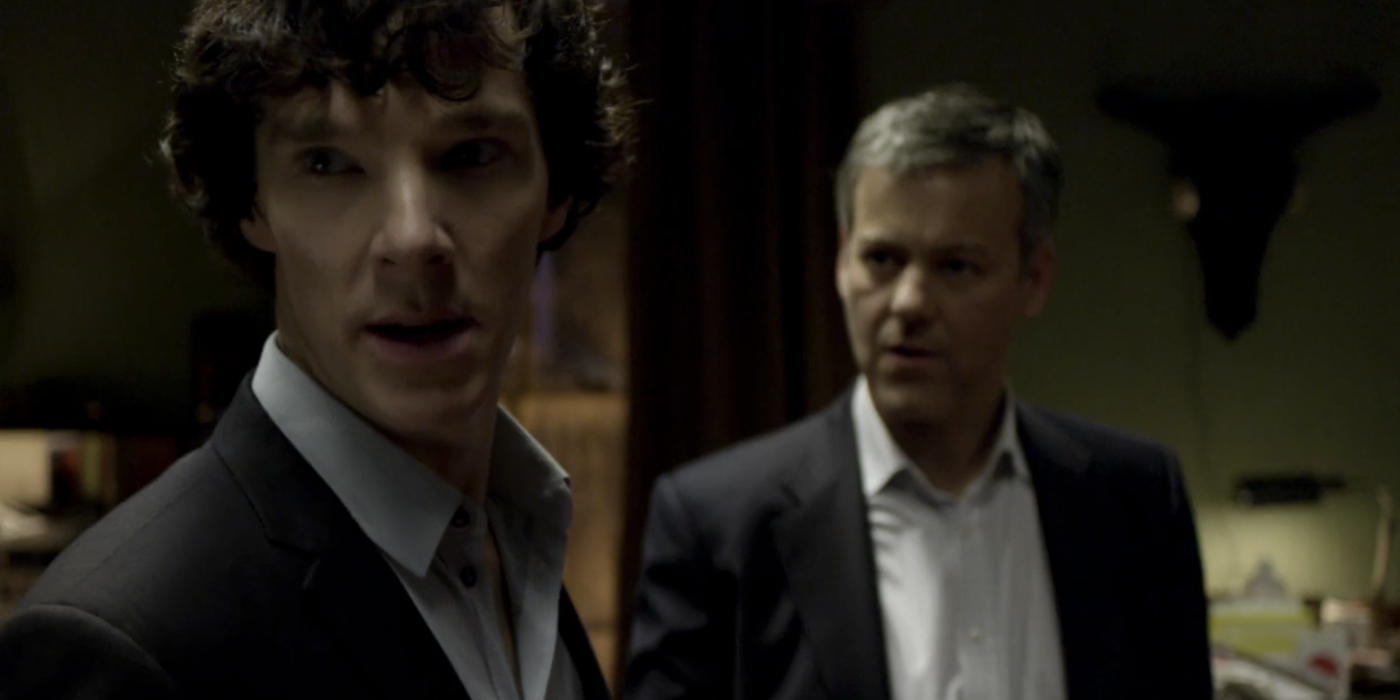 Sherlock olhando por cima do ombro enquanto estava ao lado de Lestrade no programa Sherlock da BBC