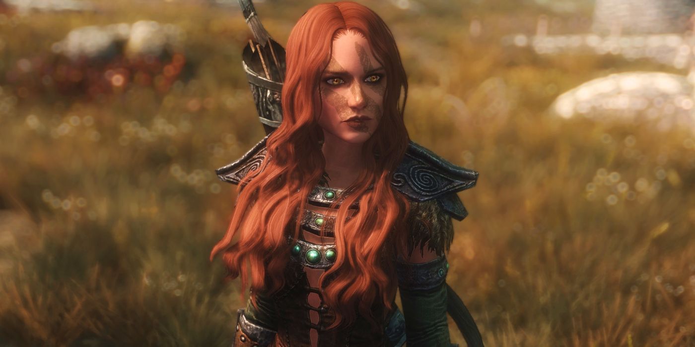 Aela The Huntress standing in a field looking into the distance in Skyrim.