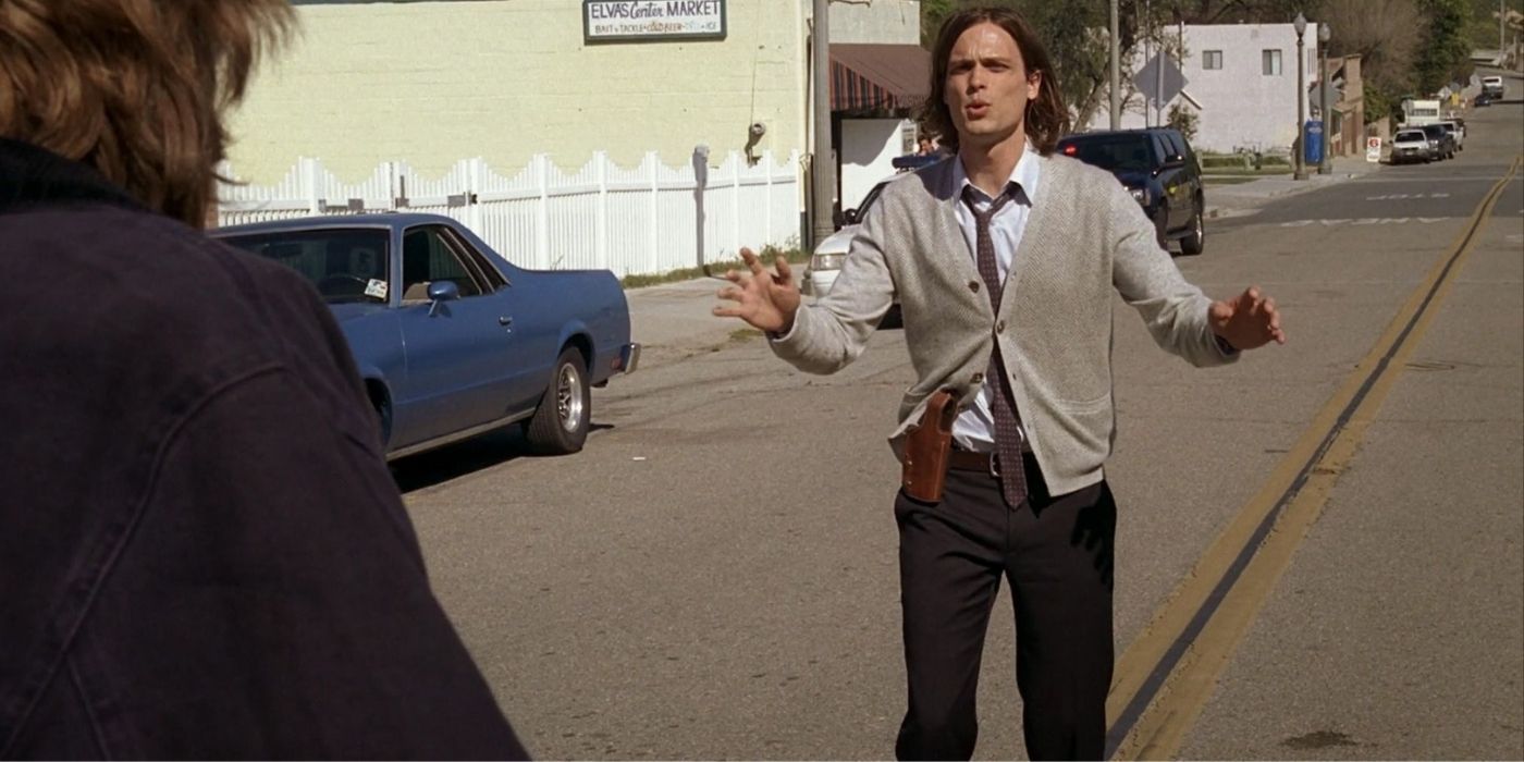 Spencer Reid standing with his arms raised in the middle of a road