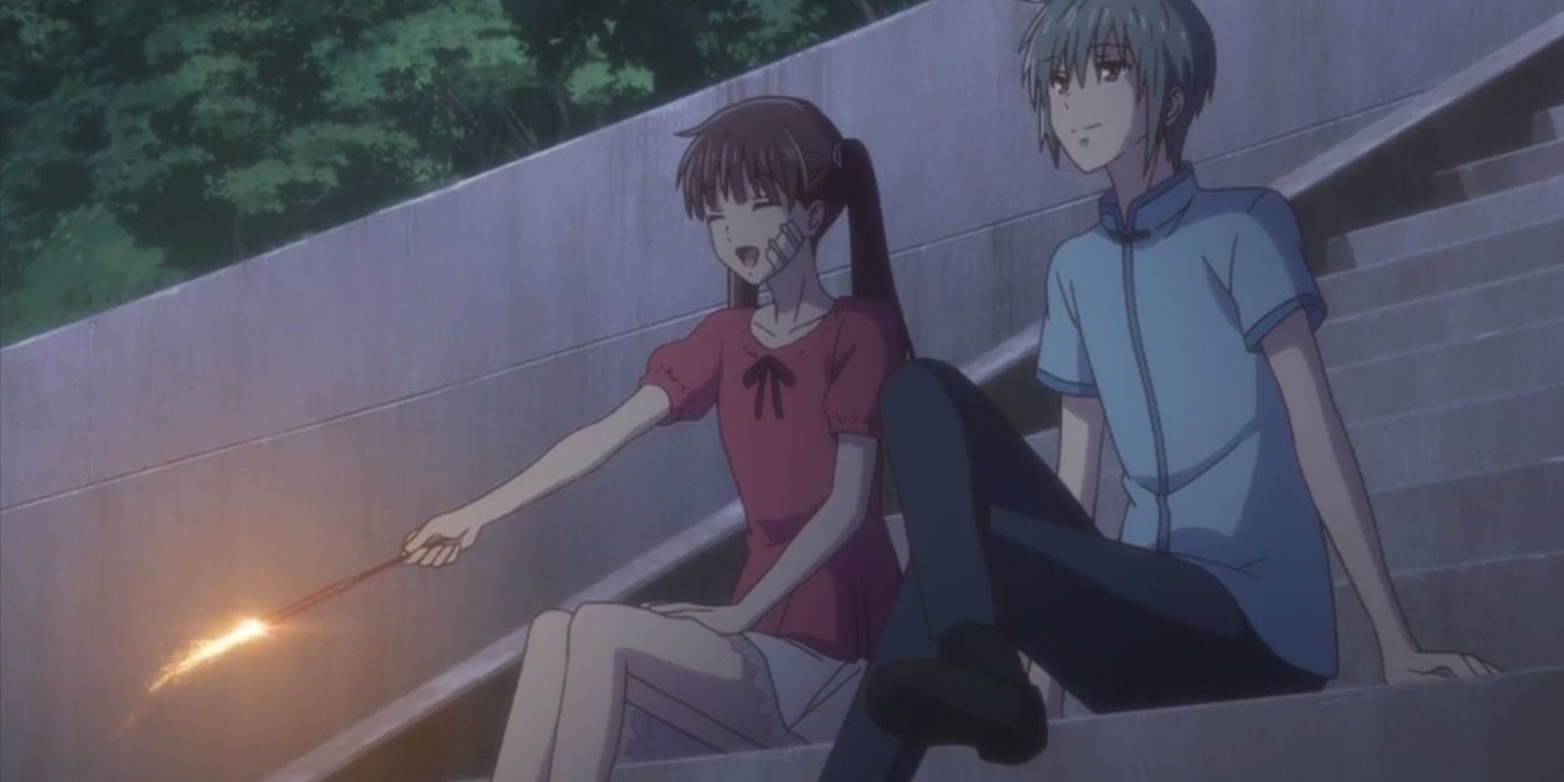 Tohru and Yuki sit on the stairs. Tohru is happily lighting a firework, Yuki looks peaceful in Fruits Basket 2019.