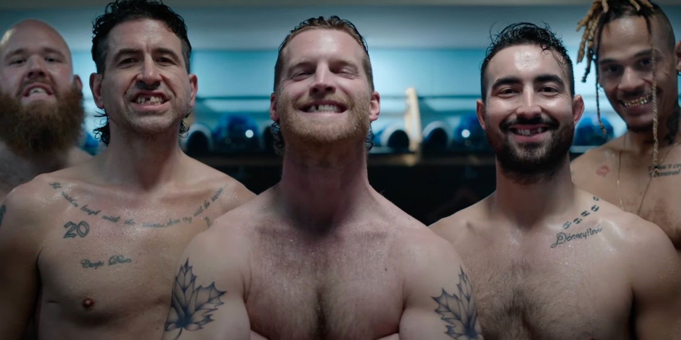 A group of shirtles men with tattoos and messed-up teeth smile for the camera.