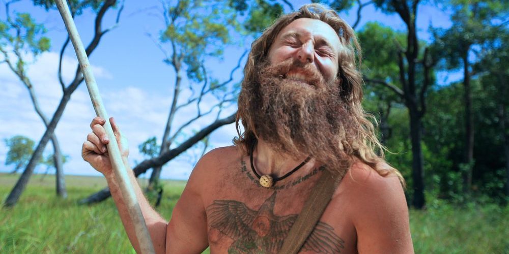 Luke holds a spear and laughs on Naked and Afraid