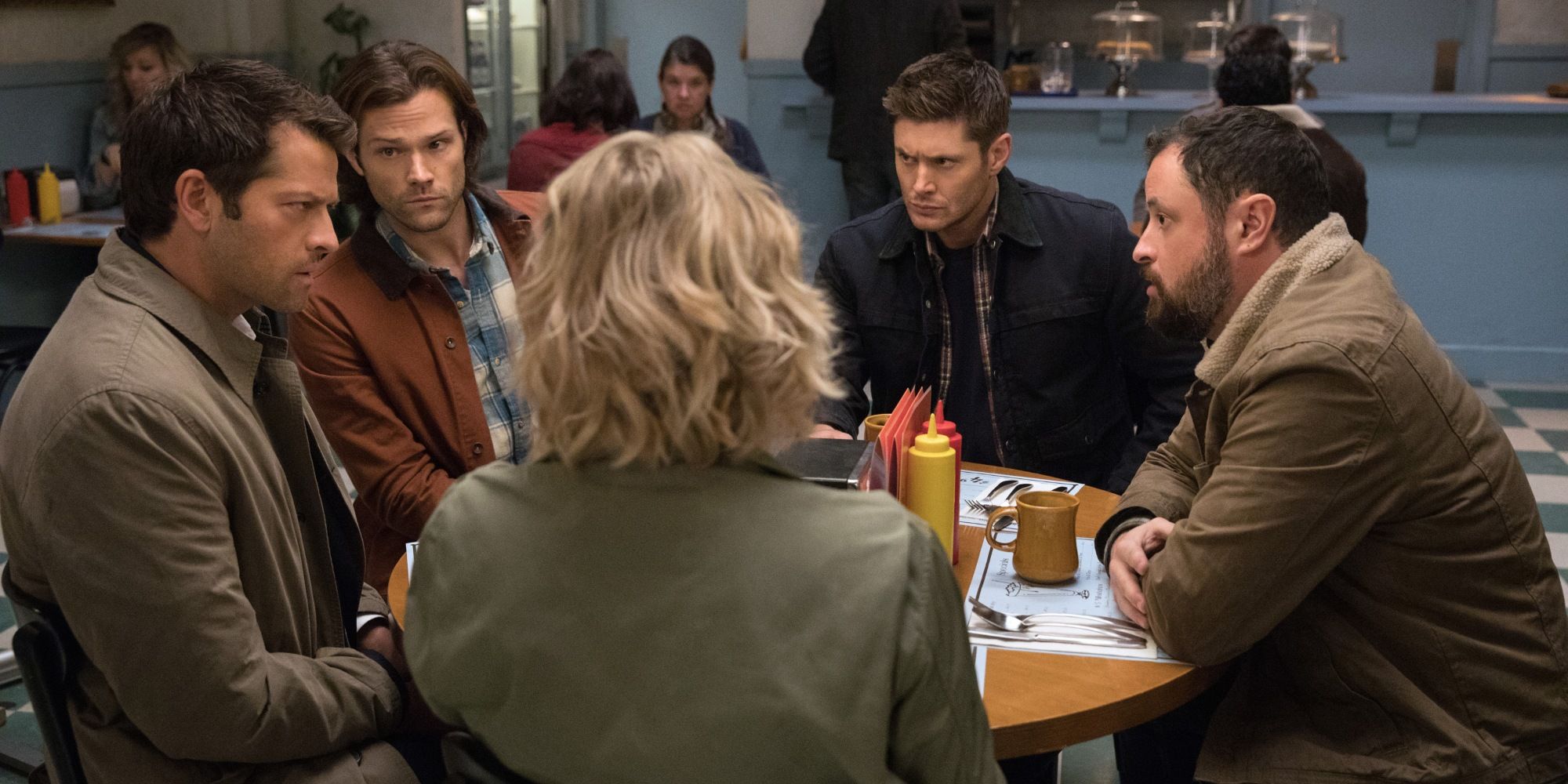 Characters from Supernatural sitting in a table otgether