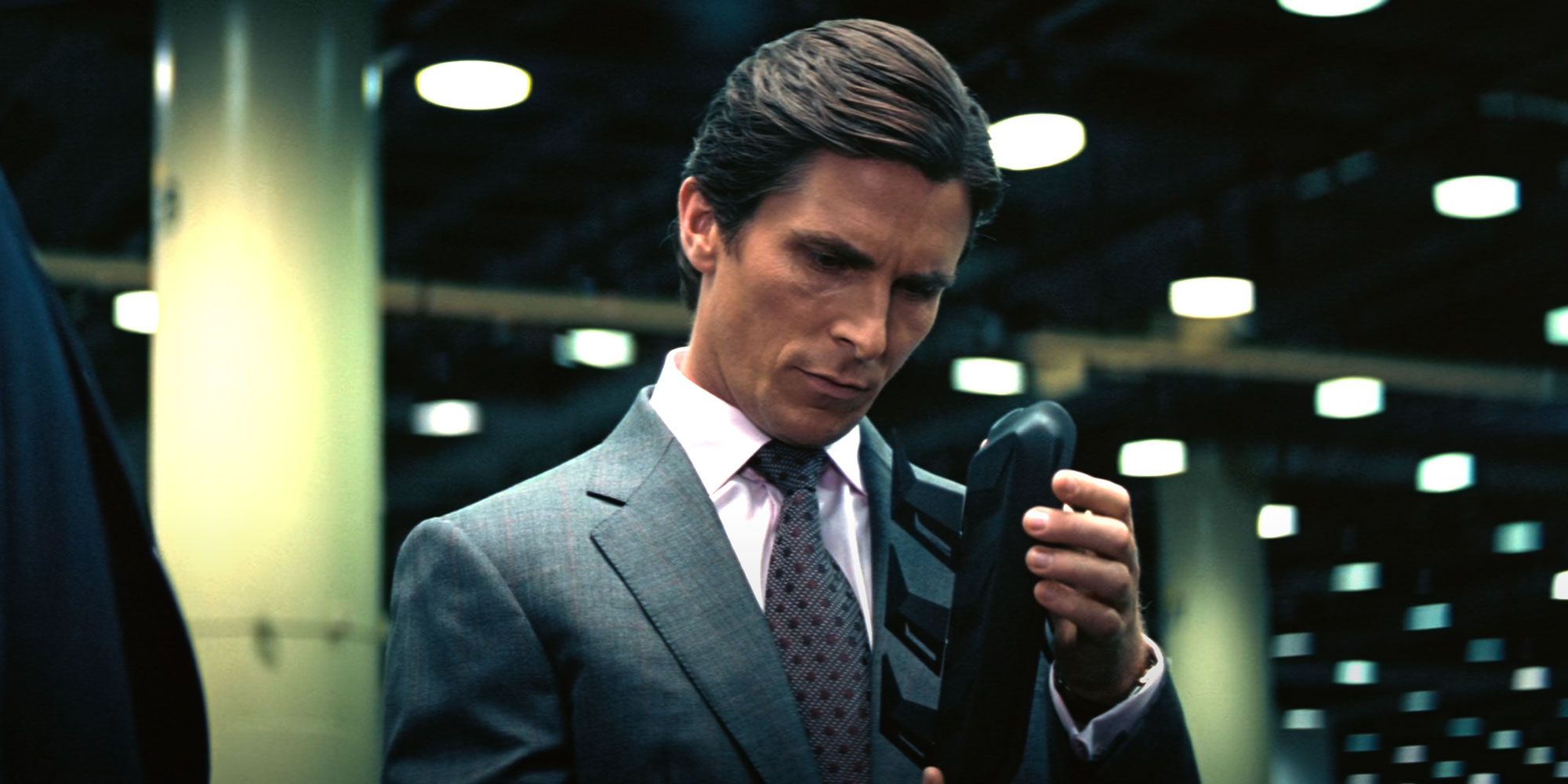 Bruce Wayne (Christian Bale) closely examines a device.
