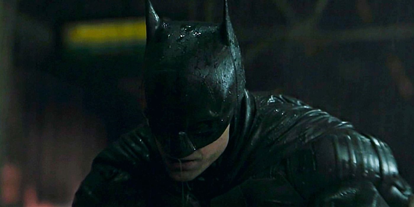 Batman crouched over a beaten gang thug in The Batman
