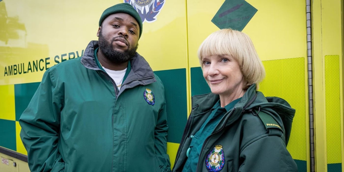 Maleek and Wendy in green uniforms in front of their ambulance on Bloods
