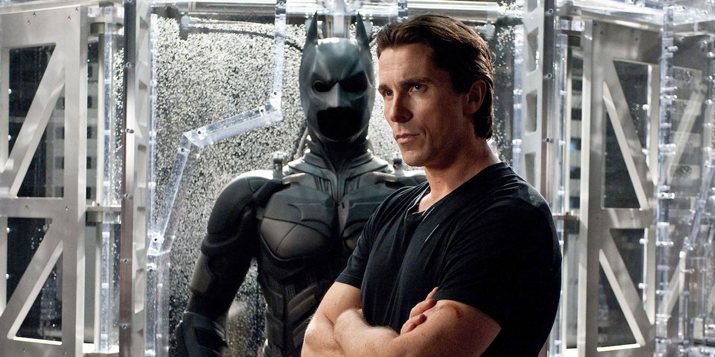 Christian Bale standing by the Batman suit.
