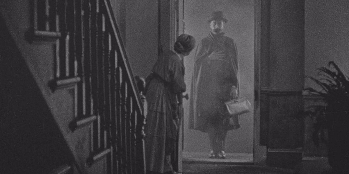 A mysterious man stands in the doorway as a woman opens the door from The Lodger