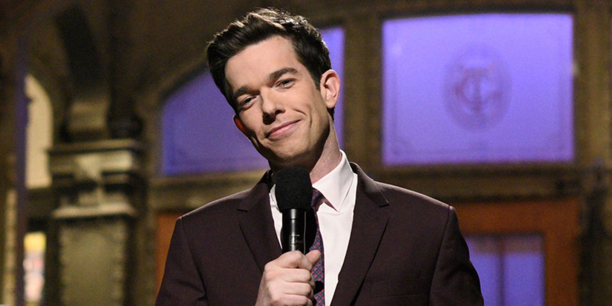 John Mulaney on stage with a microphone