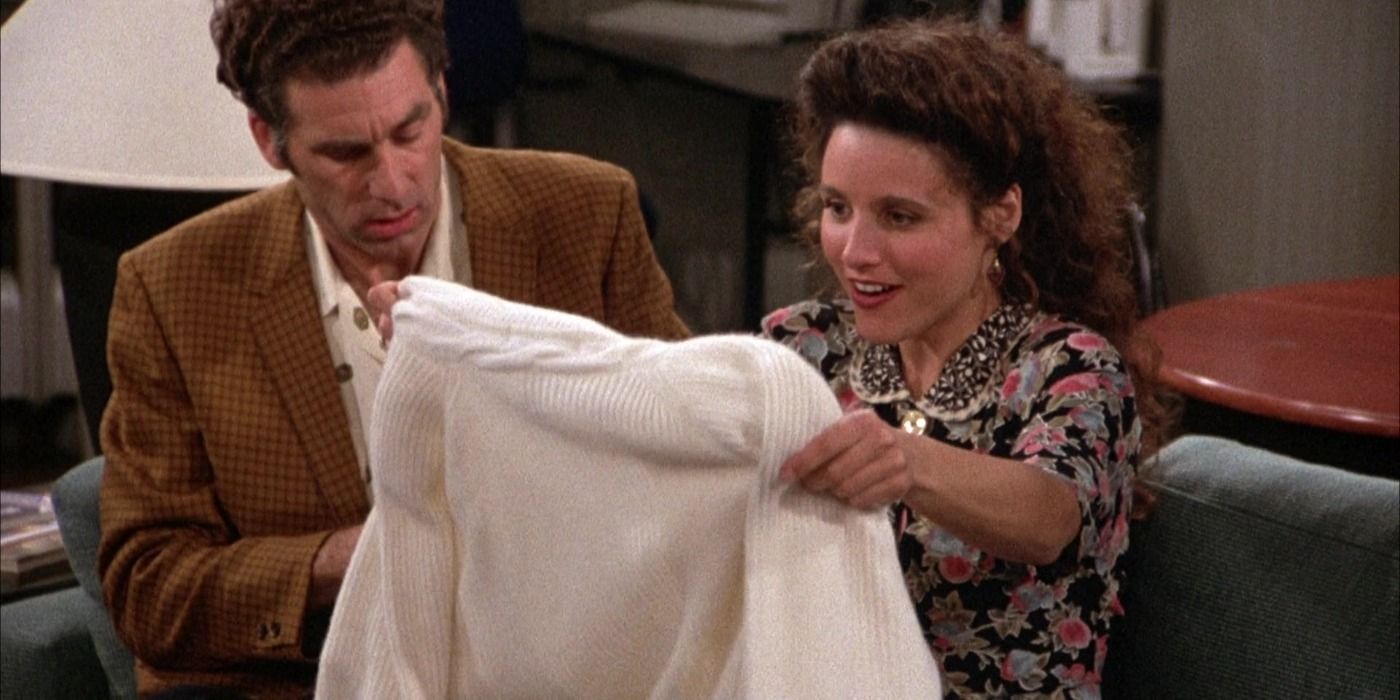 Karmer olha para Elaine enquanto ela segura um suéter de cashmere branco no Jerry's em Seinfeld
