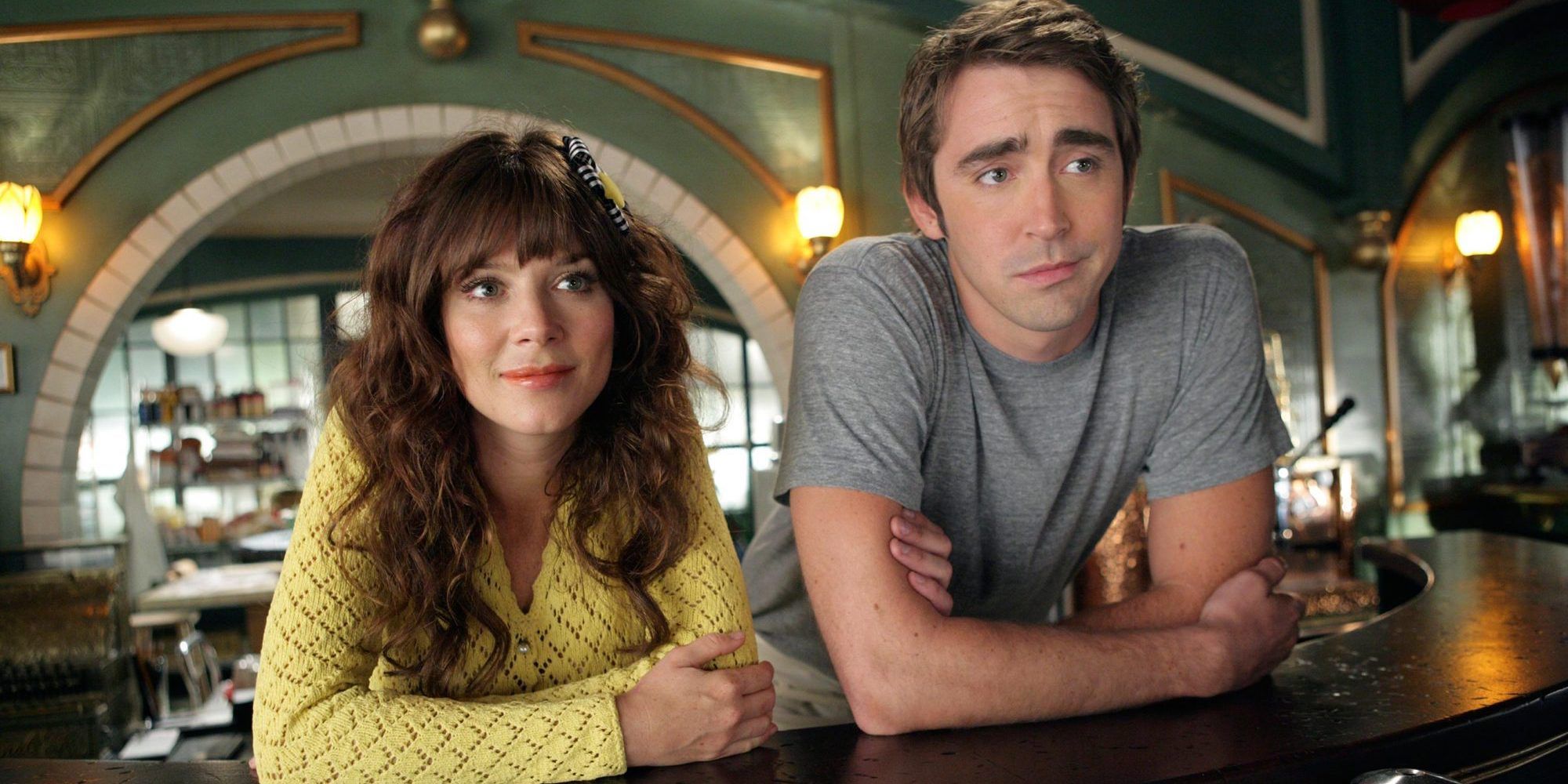 A man and woman lean on a counter while looking on from Pushing Daisies 