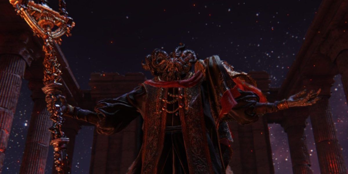 Mohg, Lord of Blood in Elden Ring. He holds his staff in his right hand while also lifting his left hand. His face is filled with horns which make it near undescribably. He stands in a dark arena with the underground portion of the map's night sky filled with glistening stars.