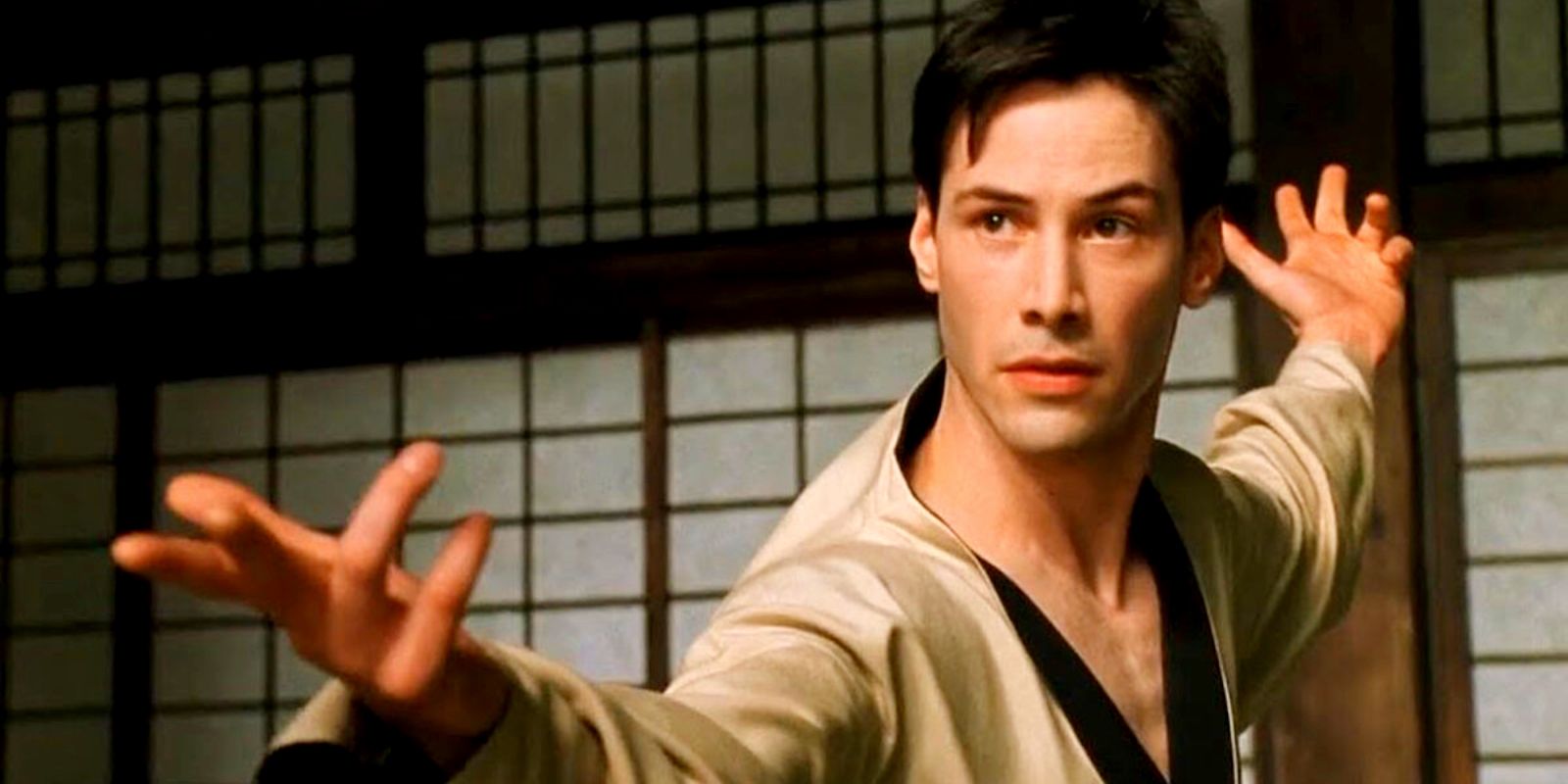 Keanu Reeves in a Dojo, holding his hands up 