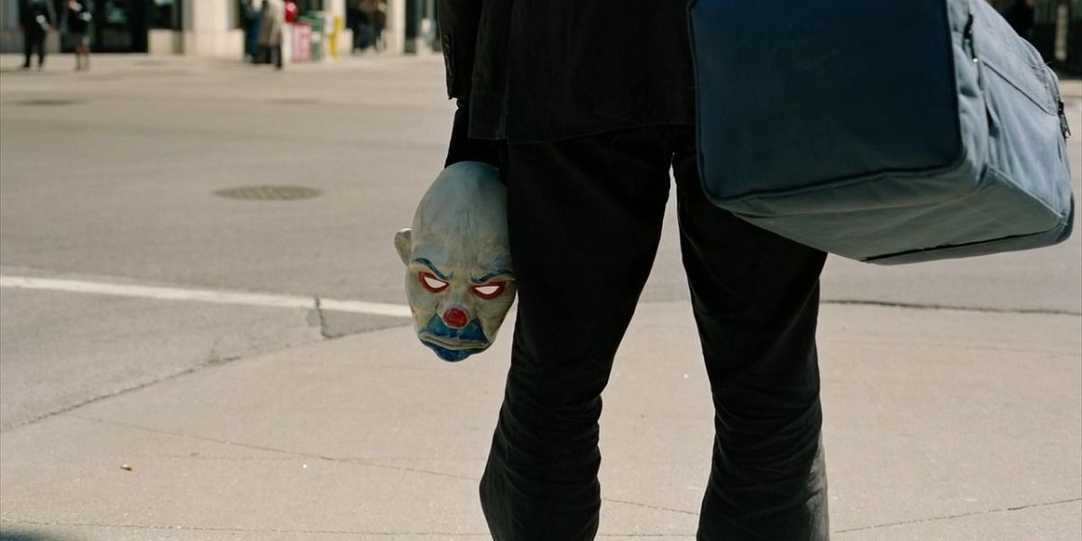 The Joker holds a clown mask in The Dark Knight.