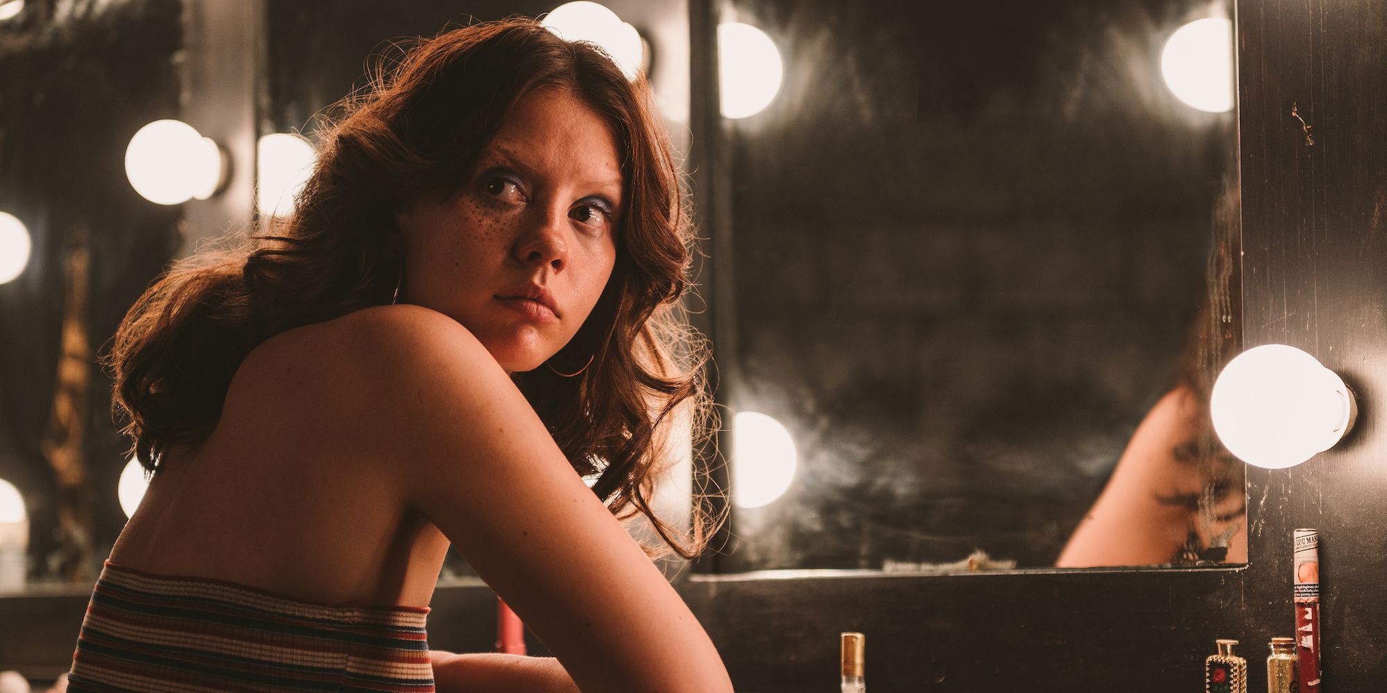 Maxine (Mia Goth) looks over her shoulder while sitting at a vanity in her dressing room in X.