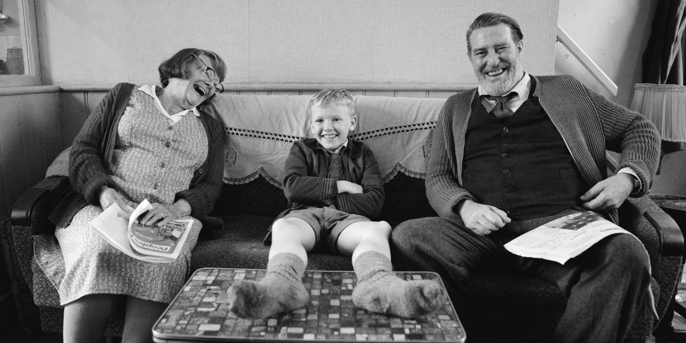 Judi Dench And Ciarán Hinds from Belfast sitting on a couch with a little boy in between them.