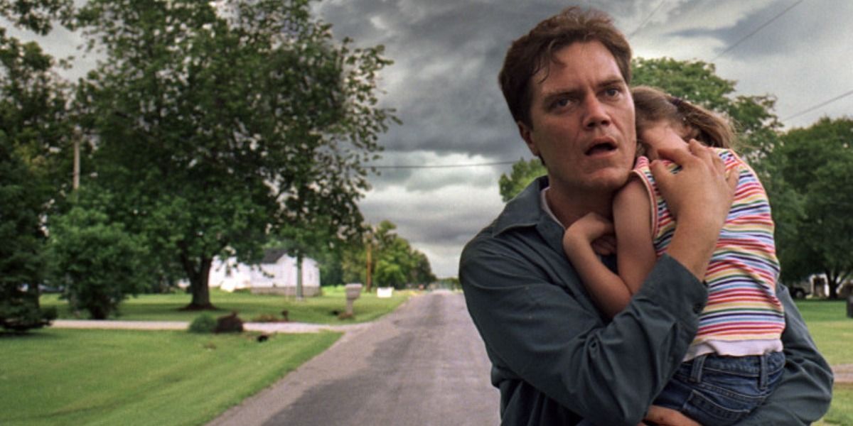Curtis holding a little girl with storm clouds behind him in Take Shelter.