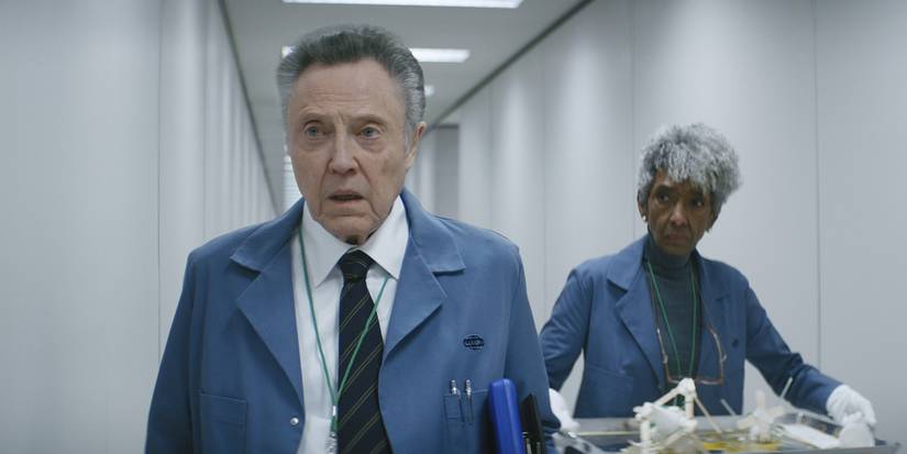 Burt from Severance, walking down the hall in a lab coat, his employee behind him.