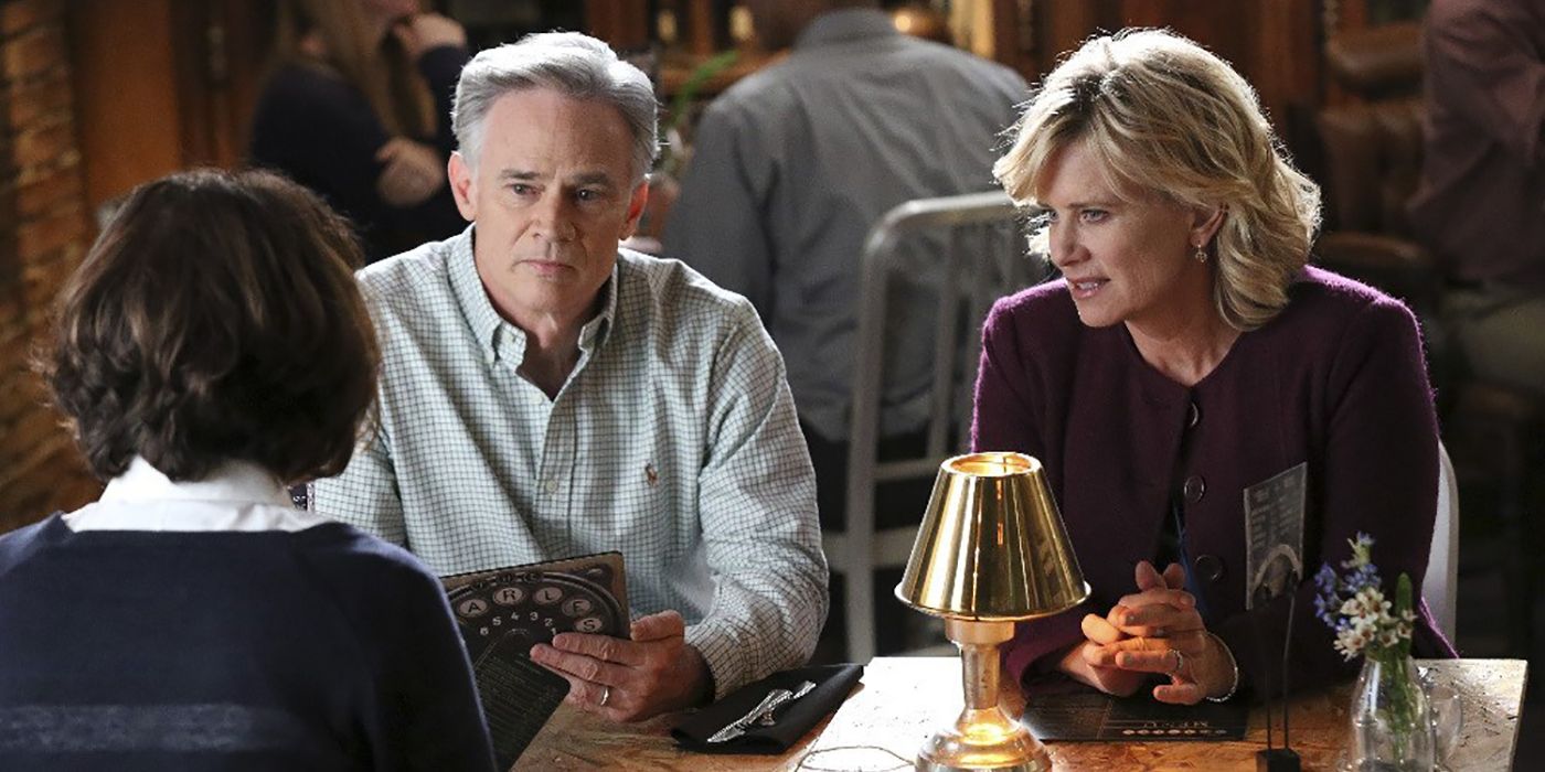 Todd Waring sitting with a woman at a dinner table talking to someone in a scene from Chasing Life.