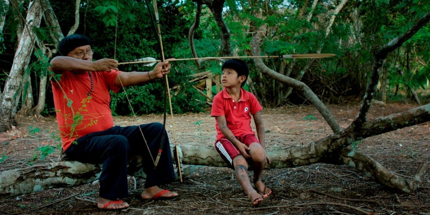 A man in the amazon shows a child how to use a bow and arrow in Ex-Shaman