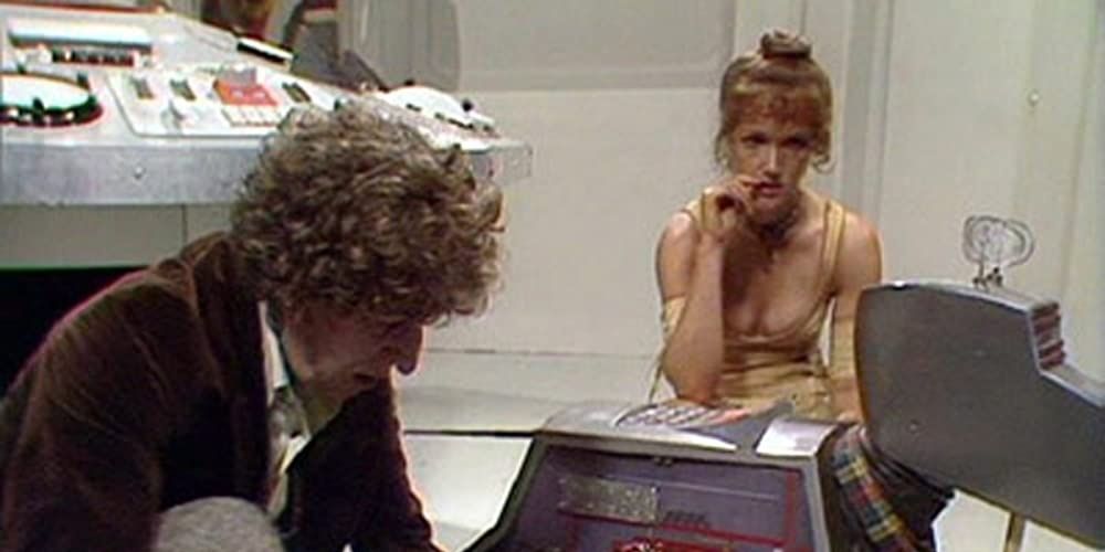 The Fourth Doctor fiddles with K9’s circuitry while Leela looks on anxiously in Image Of The Fendahl
